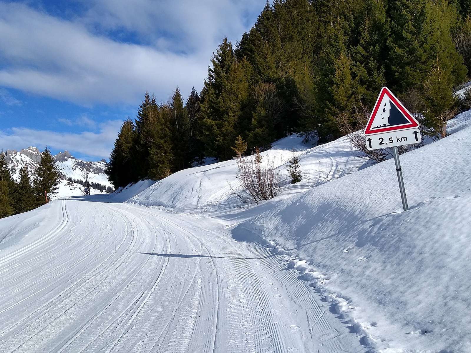 Piste de ski de fond sur la route du col de la Ramaz, panneau A19 chutes de pierre avec panonceau M2 2,5 km, Mieussy, Haute-Savoie, France.