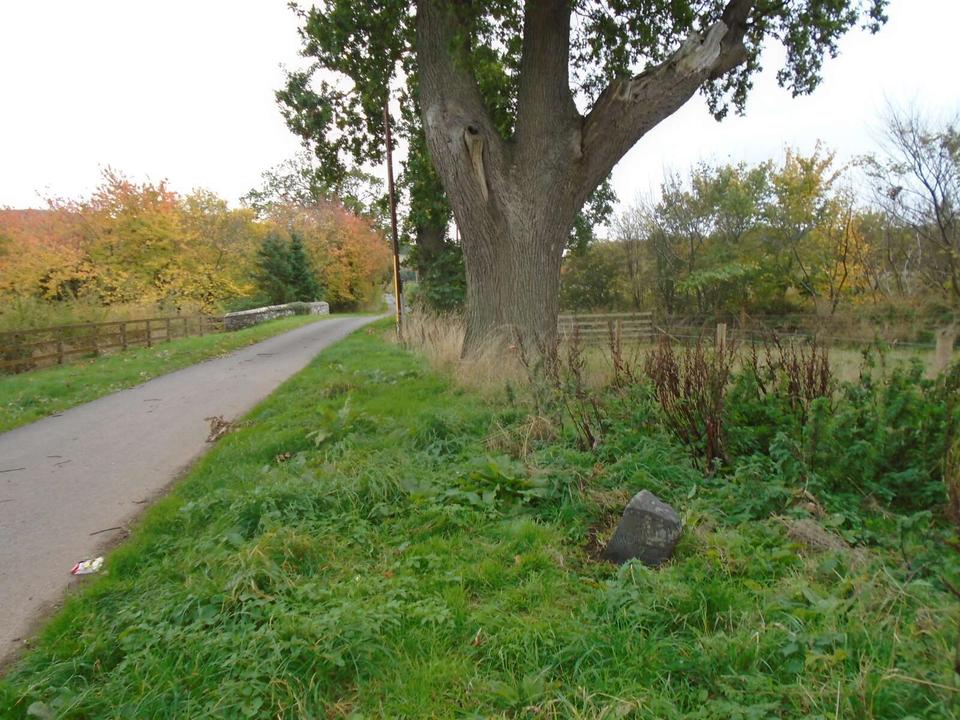 This view southwards towards the B6401 shows the milestone in relation to the bridge over the burn